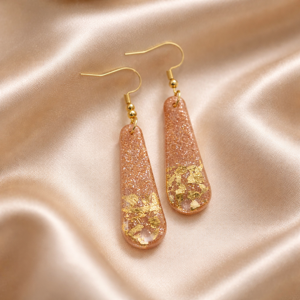 Handmade pink drop earrings with gold flakes on a soft background