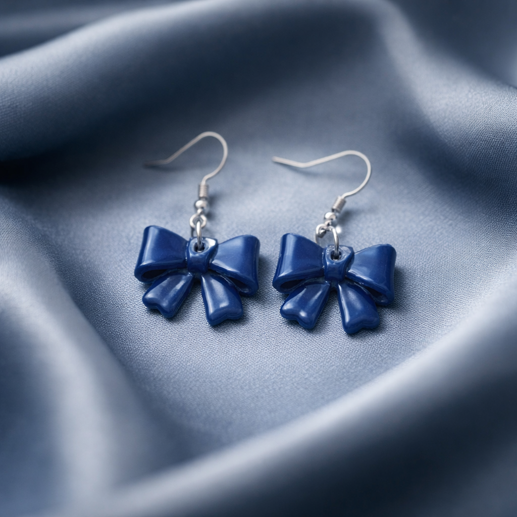 Handmade navy blue bow earrings on a soft fabric background