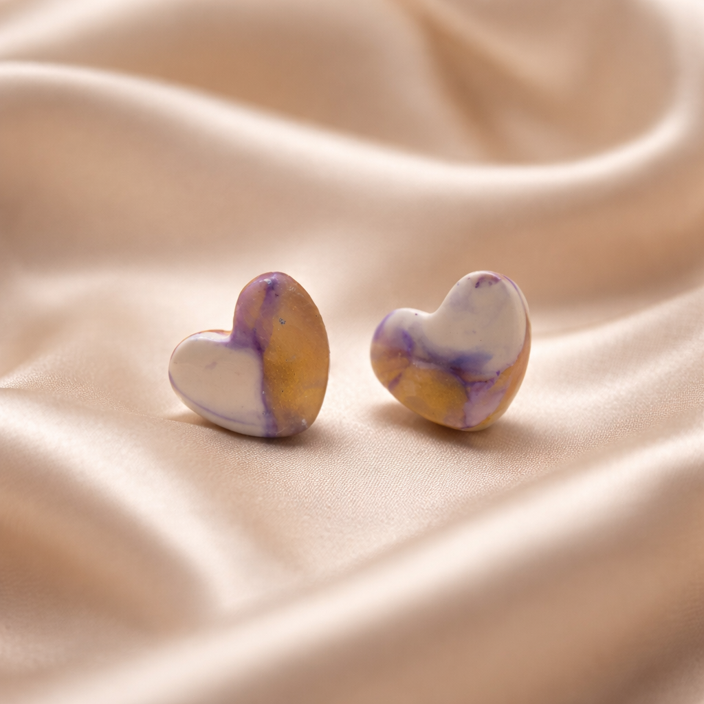 Pair of marbled heart stud earrings in white, lavender, and golden tones