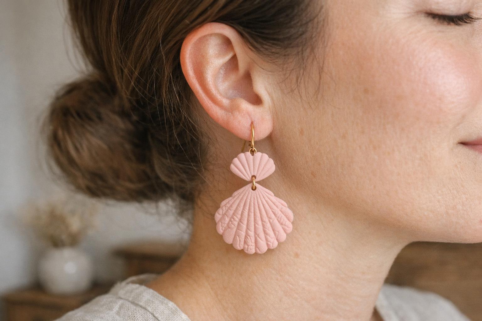 Blush pink floral-textured polymer clay teardrop earrings worn with a simple modest blouse in soft window light.